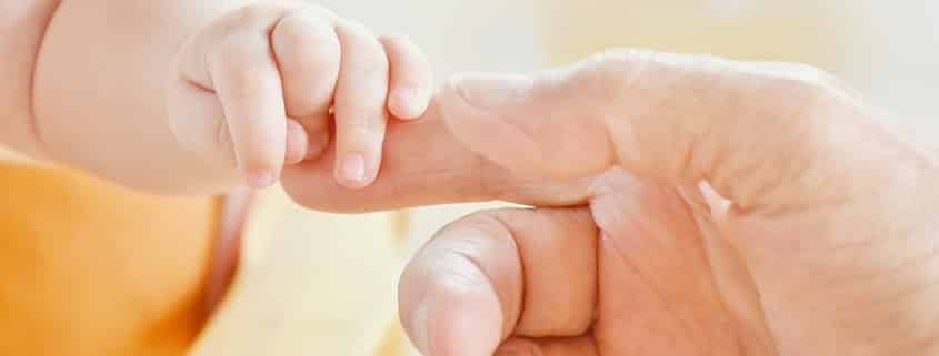 Mano de bebé agarra una mano adulta