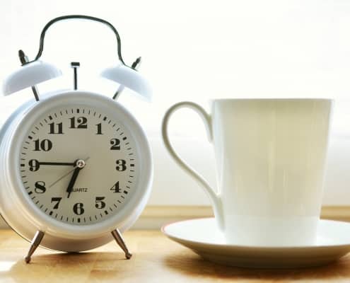 Reloj despertador junto a taza de desayuno