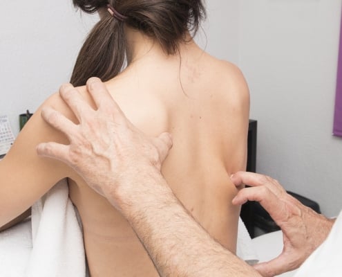 médico revisando la espalda de una paciente con posible dolor de espalda