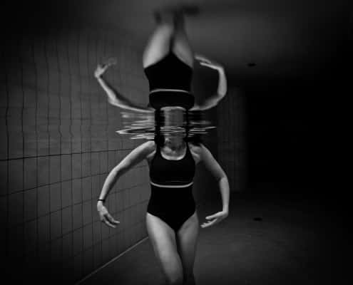 Mujer con bañador negro bajo el agua