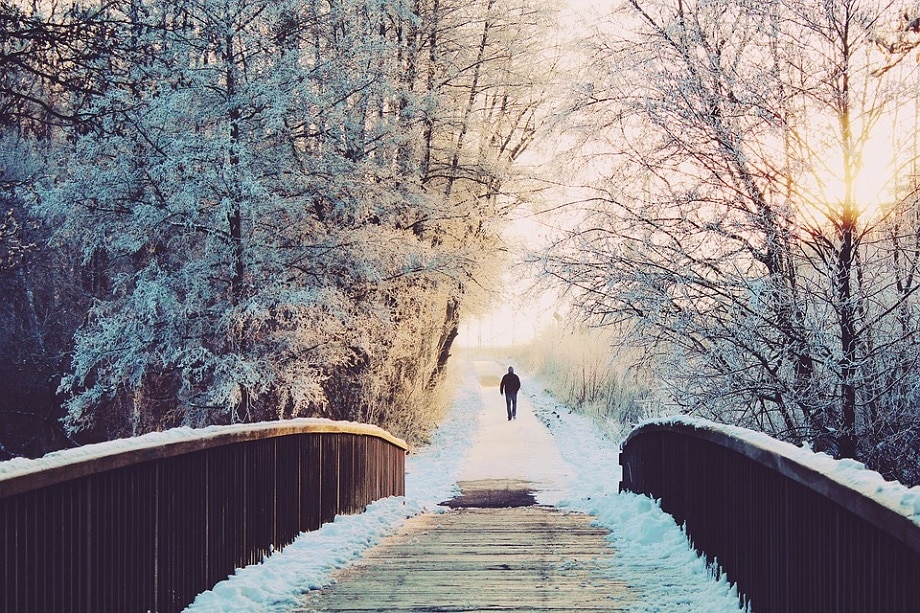 hombre alejándose de un puente en un paisaje cubierto de nieve
