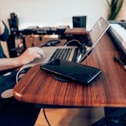 Persona utiliza un ordenador en un escritorio junto a un piano y un smartphone