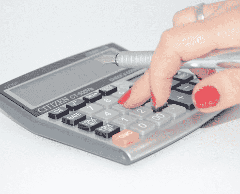 Mujer con uñas rojas utilizando una calculadora