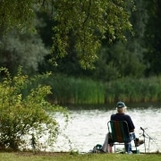 Jubilado sentado junto a un bonito lago