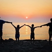 Una familia de cuatro integrantes juntas bajo una puesta son en una playa