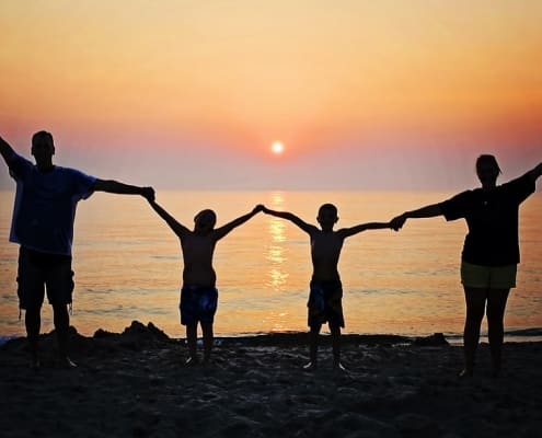 Una familia de cuatro integrantes juntas bajo una puesta son en una playa