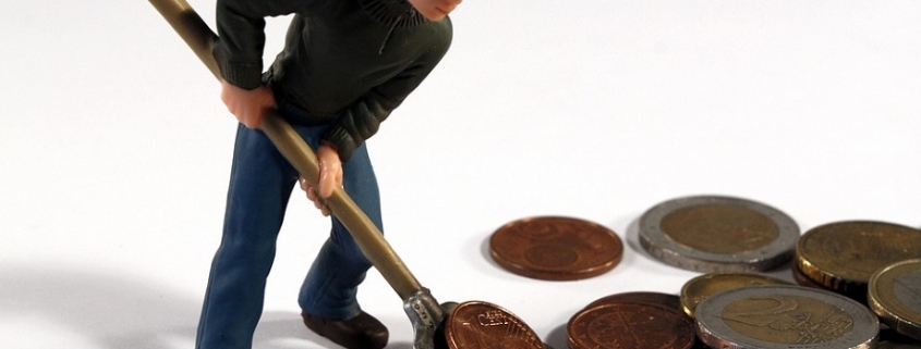 muñeco recogiendo monedas con una pala para ahorrar