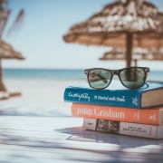 Gafas de sol apoyadas sobre unos libros en una playa paradisíaca
