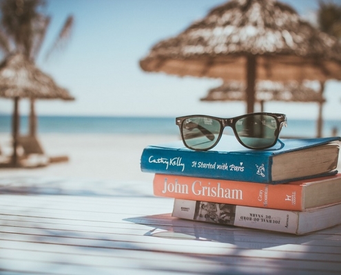 Gafas de sol apoyadas sobre unos libros en una playa paradisíaca