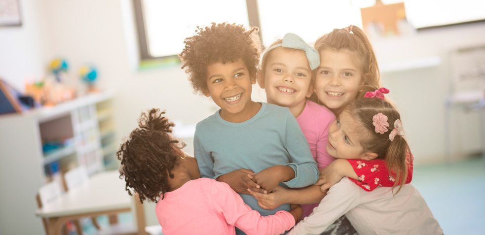 grupo de niños y niñas abrazados sonriendo tras la vacunación