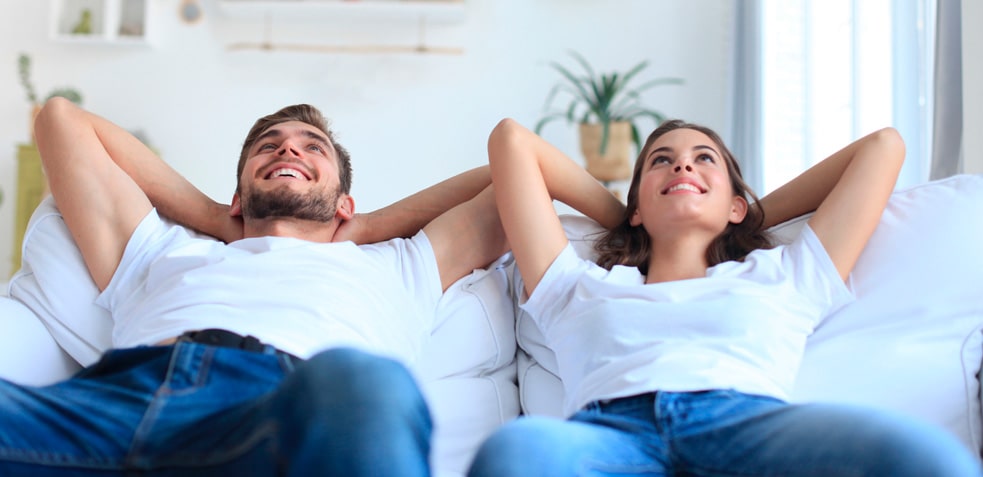 hombre y mujer sentados en el sofá y mirando al techo felizmente