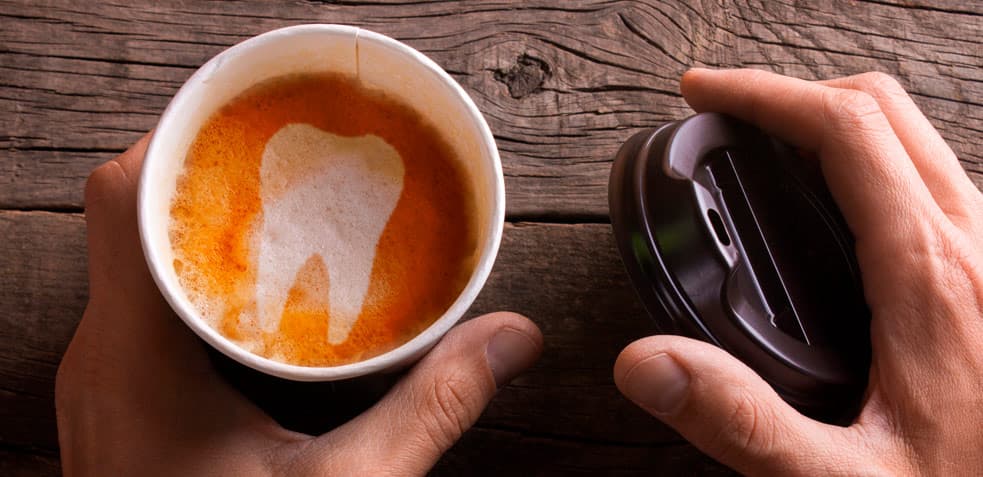 taza de café para llevar con un diente dibujado en el café