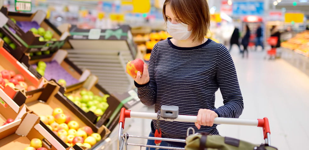 mujer comprando fruta en el supermercado con la mascarilla puesta para evitar el contagio del coronavirus