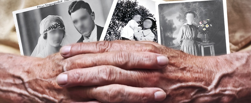 Dos manos de ancianos cruzadas bajo tres fotografías en blanco y negro