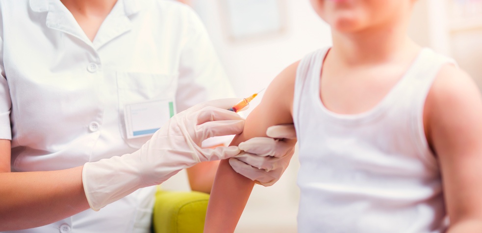 Enfermera procede a vacunar a un niño en su brazo 