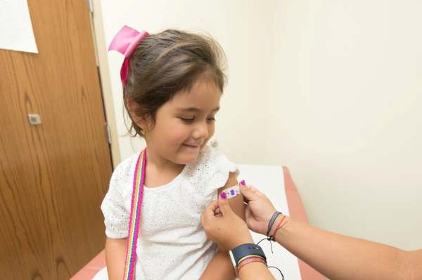 Niña con lazo rosa tras recibir la vacuna infantil del Covid-19