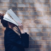Mujer con libro tapándose la cara