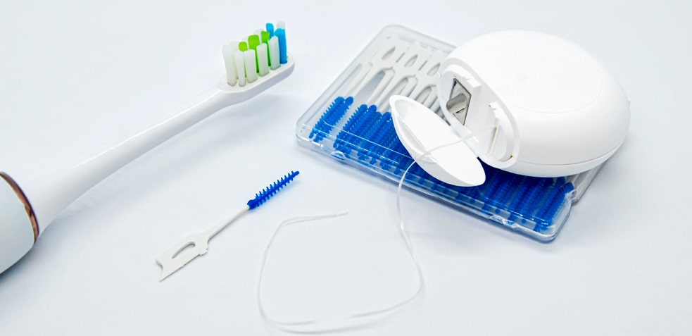 Cepillo de dientes eléctrico junto a hilo dental