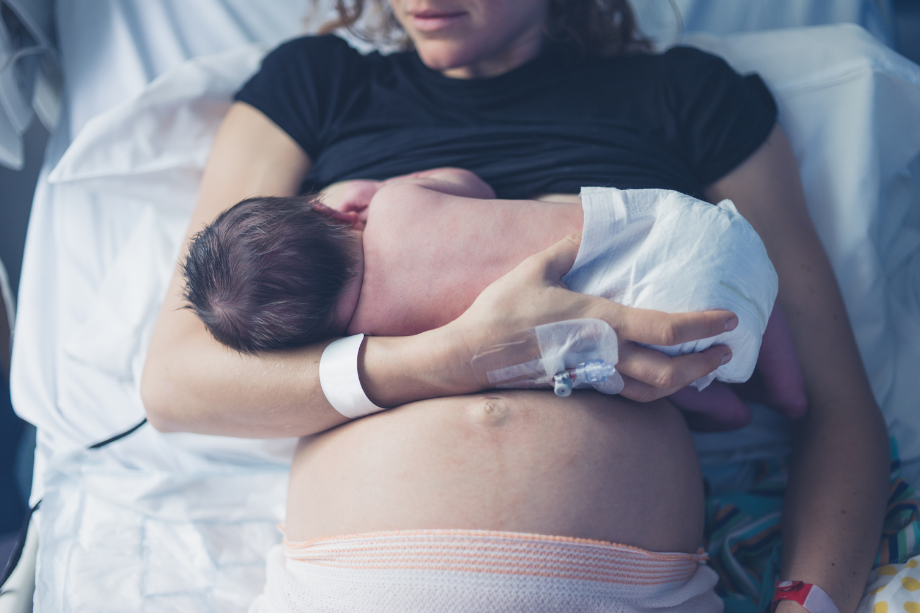 Madre da el pecho a su bebé recién nacido en la cama de un hospital