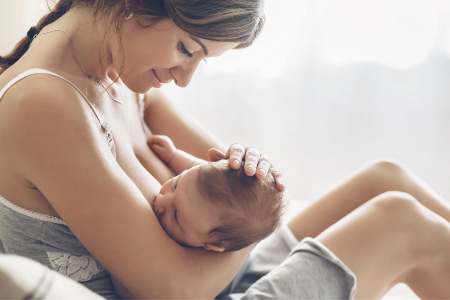Madre joven da el pecho a su bebé mientras le acaricia la cabeza