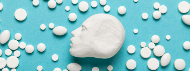 figura de una cabeza humana junto a diferentes tipos de pastillas en un fondo azul turquesa