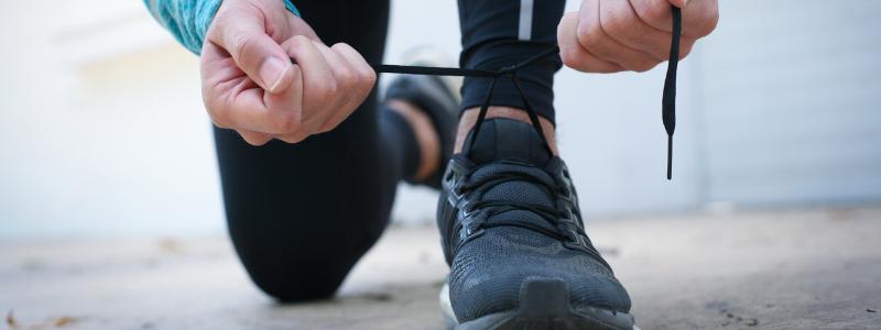Hombre atándose los cordones de sus zapatillas deportivas antes de salir a correr