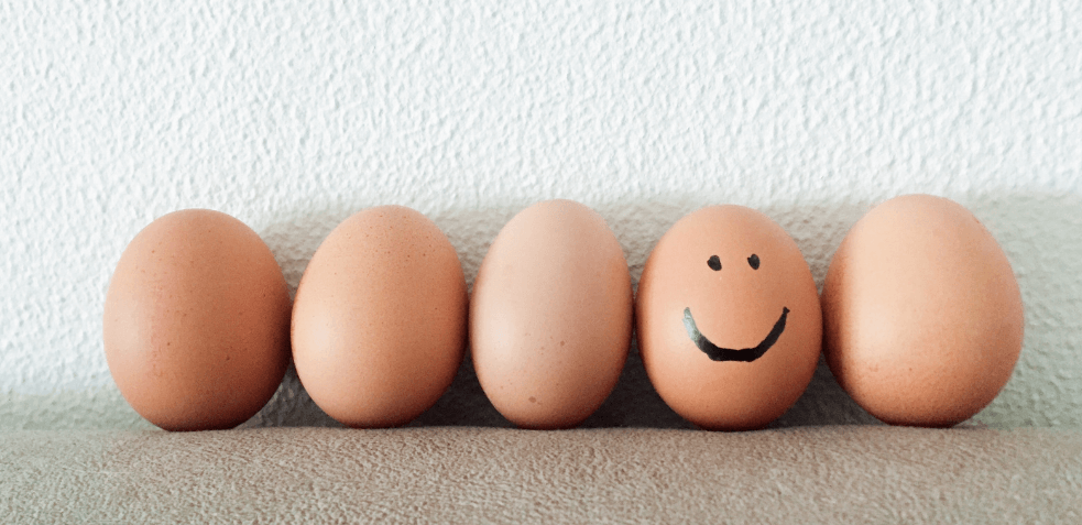 un huevo sonriente entre otros lisos demostrando lo que destaca sonreír