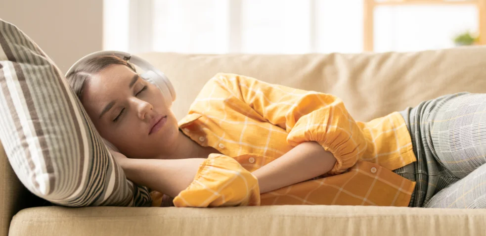 Mujer durmiendo en un sofá con auriculares