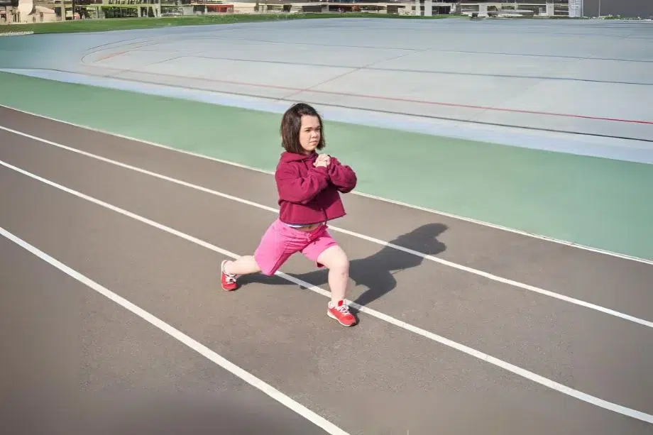 Persona con acondroplasia realizando estiramientos en una pista de atletismo