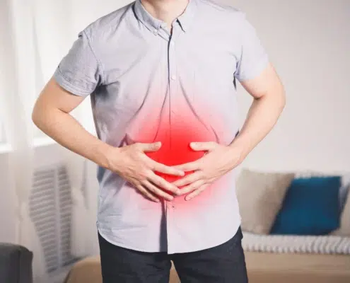 Persona con dolor abdominal agudo sosteniéndose el estómago, representando síntomas de colitis ulcerosa