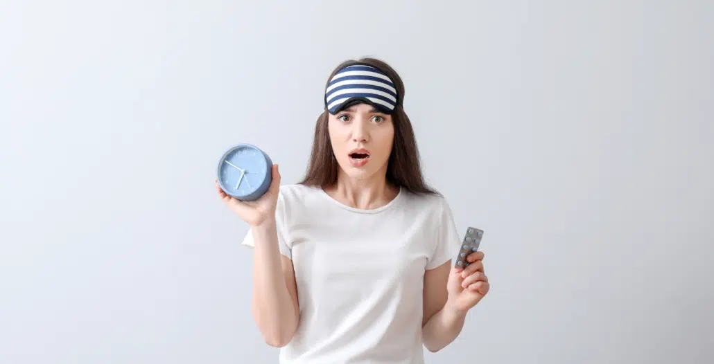 Mujer preparada para dormir, representando que no puede dormir y recurriendo a pastillas