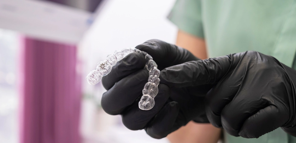 Dentista sujetando unos brackets invisibles