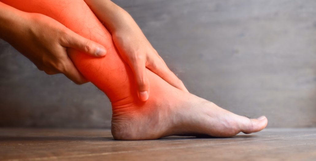 Manos sujetando gemelos y tobillo por retención de líquidos