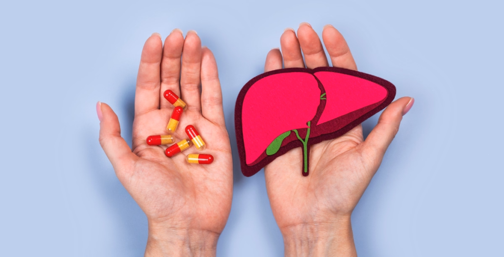 Manos sosteniendo comprimidos y una figura de un hígado
