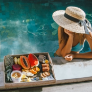 Mujer comiendo en el bordillo de la piscina